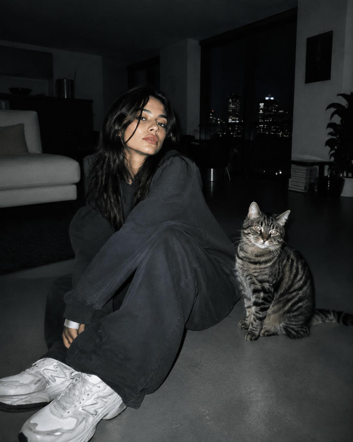 A woman sitting on the floor of a warm minimal interior with her cat